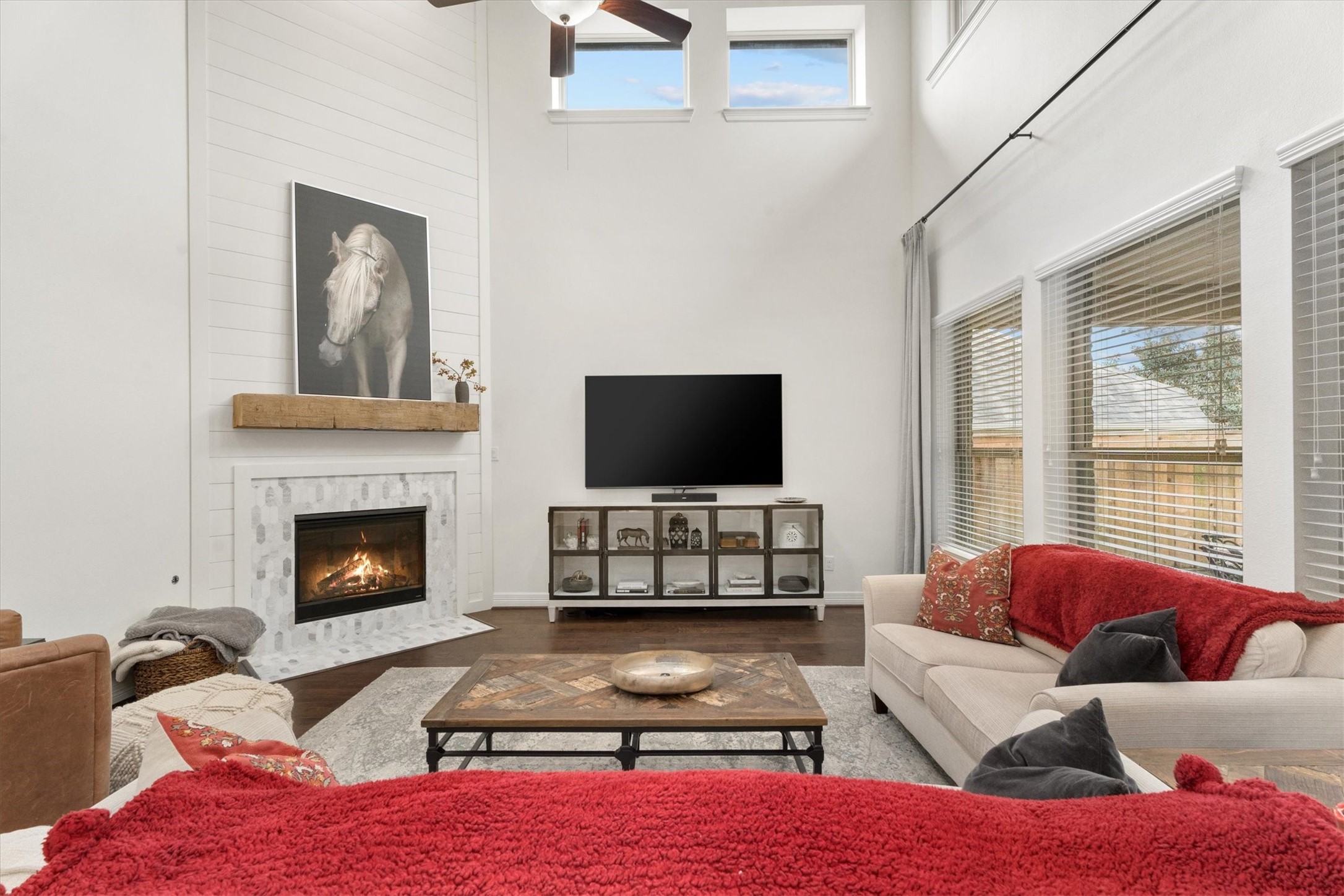 27121 Holtwood Grove Road Magnolia, TX 77354 - Photo 14 of 50 Step into this spacious and light-filled family room, where soaring ceilings and an abundance of windows create an airy, open feel. The centerpiece is the beautifully updated fireplace, showcasing modern shiplap detailing, an elegant tile surround, and a charming natural wood mantel – the perfect blend of style and warmth. Whether hosting guests or enjoying a quiet evening, this room offers the ideal setting.