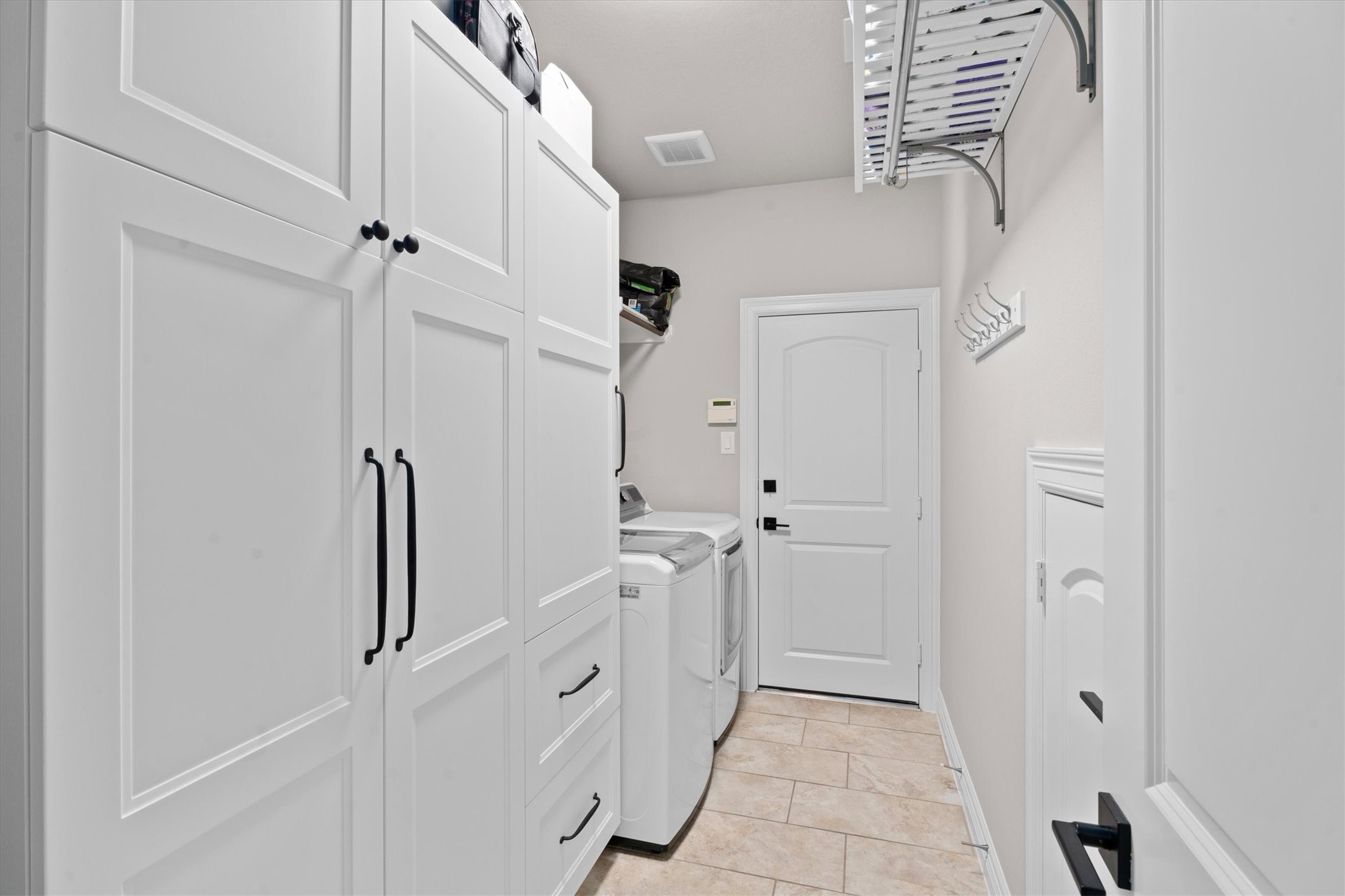 27121 Holtwood Grove Road Magnolia, TX 77354 - Photo 25 of 50 The well-appointed utility room offers exceptional storage with custom floor-to-ceiling cabinets, providing ample space to keep everything organized. Conveniently located with direct access to the garage, this functional space seamlessly blends practicality and style.