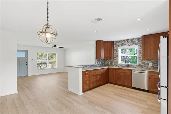 a kitchen with stainless steel appliances granite countertop a stove a sink dishwasher a refrigerator and a dining table with wooden floor