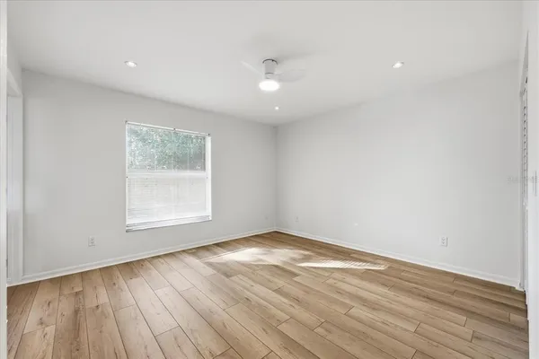 an empty room with wooden floor and windows