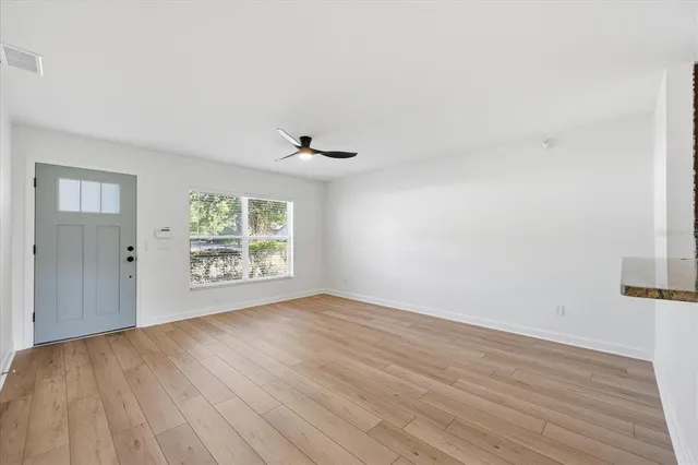 a view of an empty room with wooden floor and a window