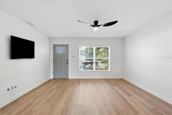 a view of an empty room with wooden floor and a window