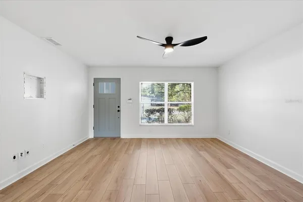 a view of an empty room with wooden floor and a window