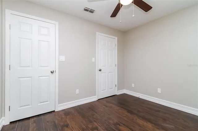 an empty room with a ceiling fan and wooden floor
