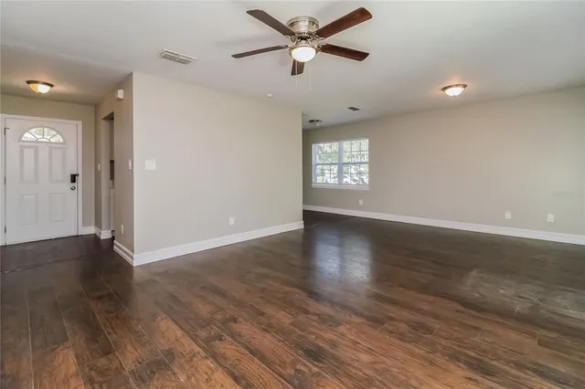 a view of an empty room with wooden floor and a window