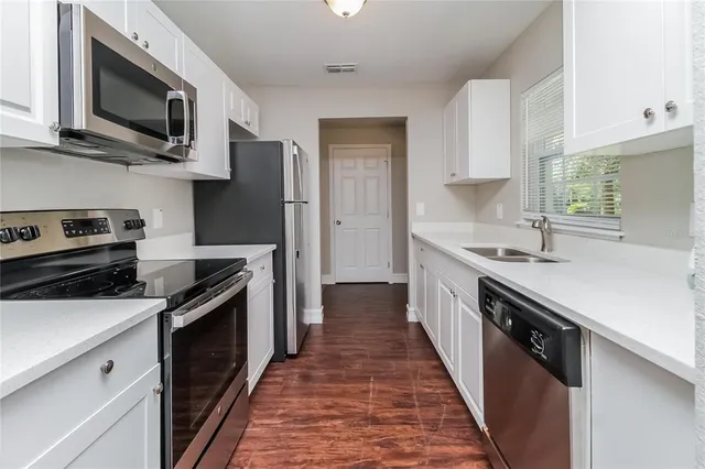 a kitchen with stainless steel appliances a sink dishwasher a stove top oven a refrigerator with grey cabinets