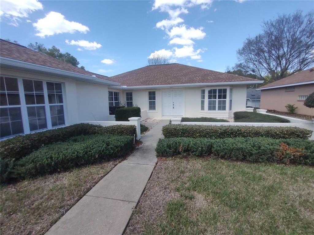7257 Southwest 115th Place Ocala, FL 34476 - Photo 4 of 18 a front view of a house with a garden and trees