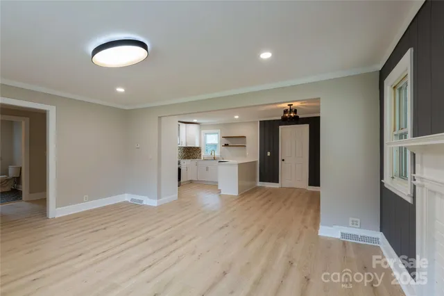 a view of an empty room with a window and wooden floor