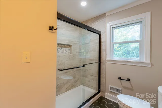 a bathroom with a toilet a sink a glass door a shower and a mirror