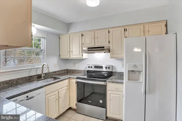 a kitchen with granite countertop a refrigerator sink and cabinets