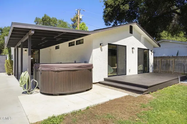 a backyard of a house with large trees and outdoor seating