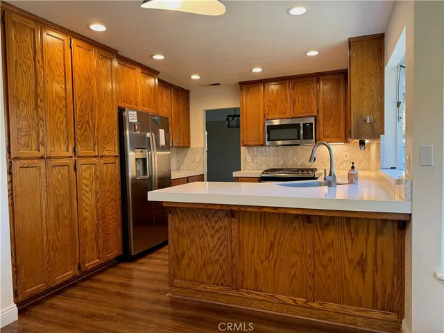 a kitchen with stainless steel appliances granite countertop a refrigerator a stove and a sink with wooden floor