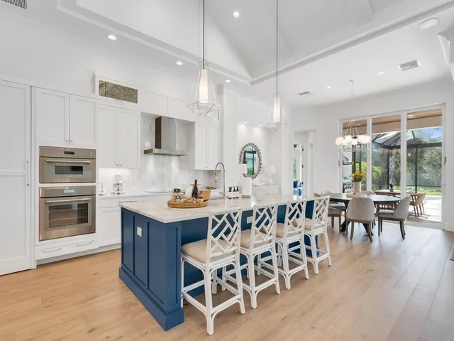 a kitchen with cabinets a sink dishwasher a dining table and chairs with wooden floor