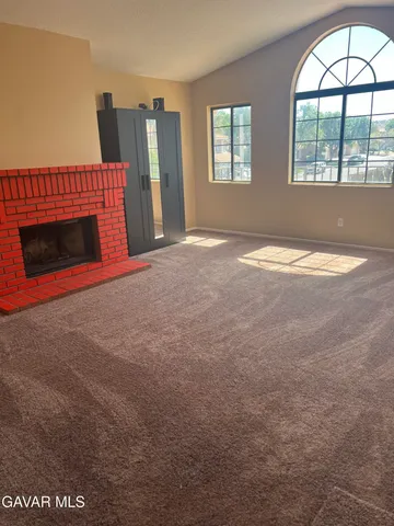 an empty room with windows and fireplace