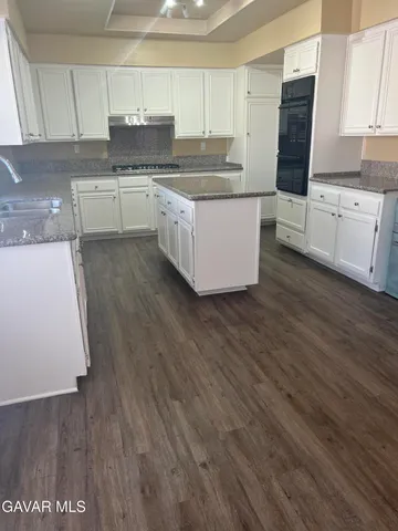 a kitchen with stainless steel appliances wooden floors and wooden cabinets
