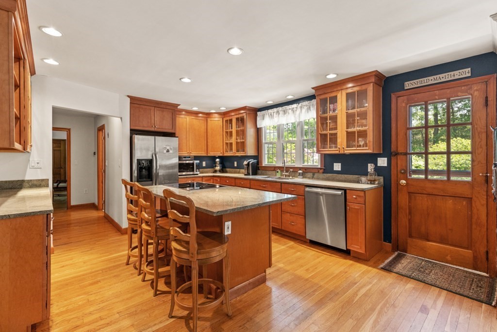 8 Candlewood Road Lynnfield, MA 01940 - Photo 16 of 41 a kitchen with stainless steel appliances granite countertop a stove a refrigerator a sink a dining table and chairs with wooden floor