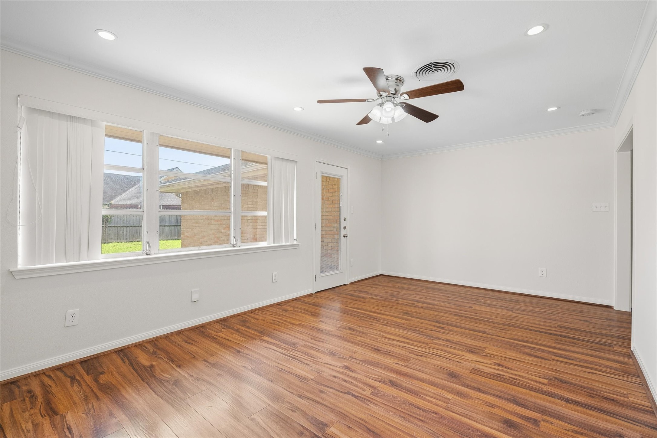 3331 Arbor Street Houston, TX 77004 - Photo 15 of 30 Living room with large windows, hardwood flooring, and a ceiling fan. Neutral walls and recessed lighting create a welcoming space, with a door leading to the backyard.