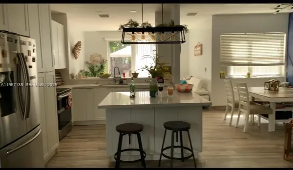 a kitchen with stainless steel appliances a dining table chairs refrigerator and sink