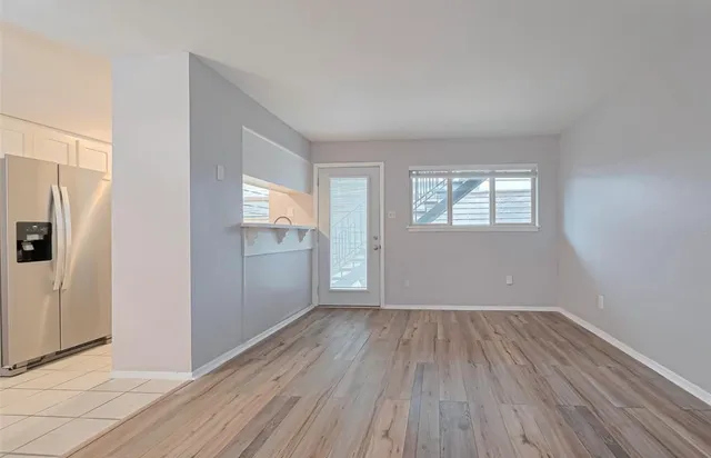 a view of a refrigerator in kitchen and an empty room