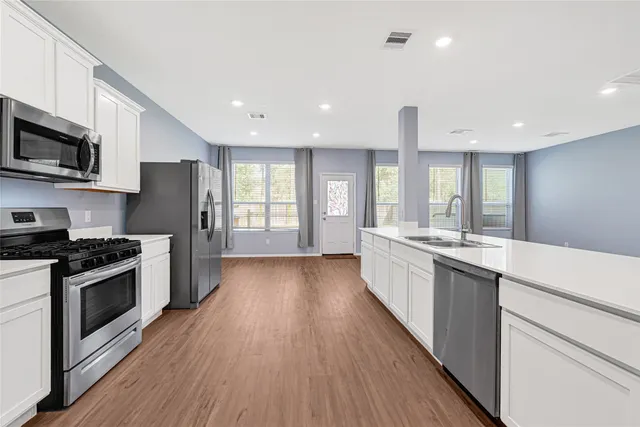 a large kitchen with stainless steel appliances granite countertop a lot of counter space and wooden floor