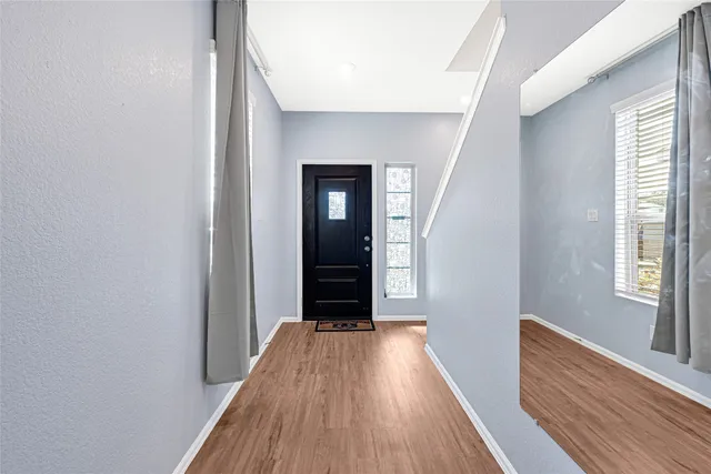 a view of a hallway with wooden floor and a bathroom