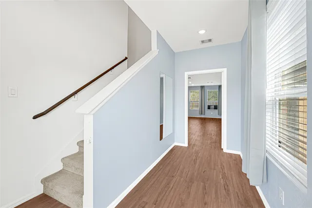 a view of a hallway with wooden floor and staircase