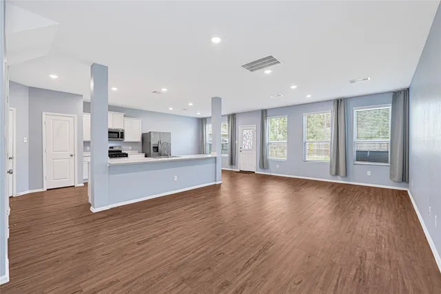 a view of an empty room with window and wooden floor