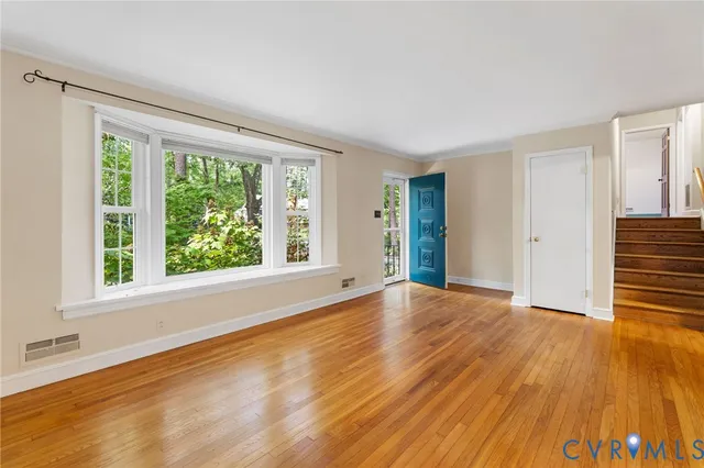 a view of an empty room with wooden floor and a window