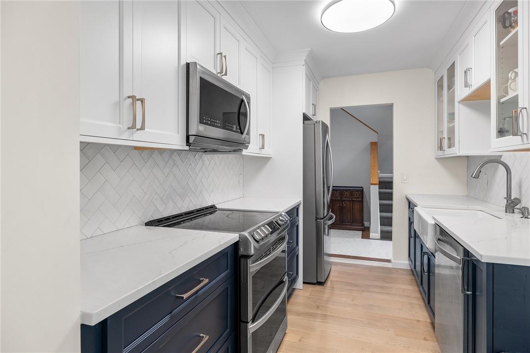14 Brookwood Road New Rochelle, NY 10804 - Photo 1 of 1 Kitchen featuring appliances with stainless steel finishes, white cabinetry, tasteful backsplash, and light hardwood / wood-style floors