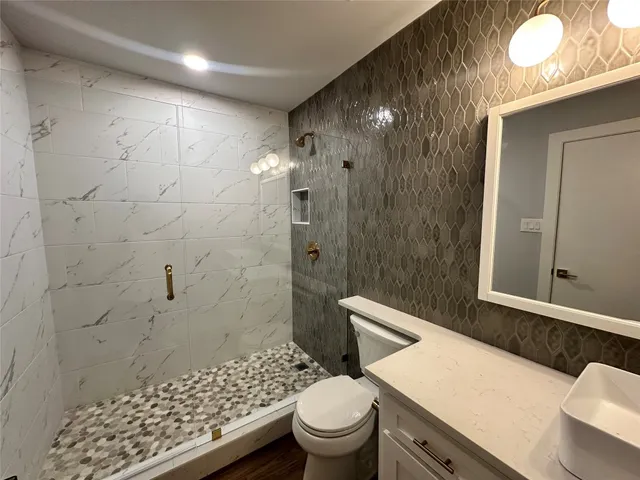 a bathroom with a sink a toilet a shower and a window