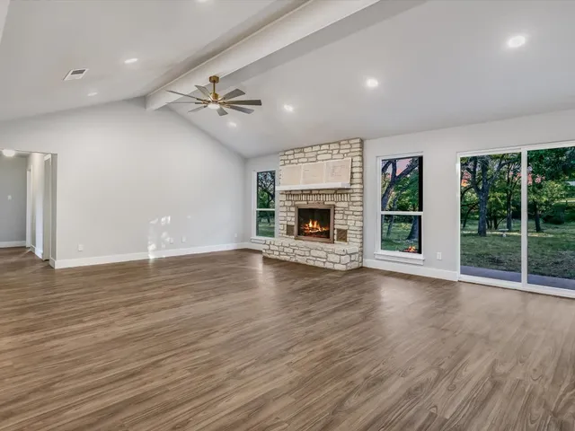 an empty room with windows fireplace and wooden floor