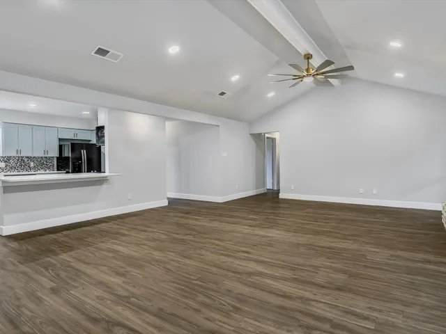 a view of a kitchen an empty room and wooden floor