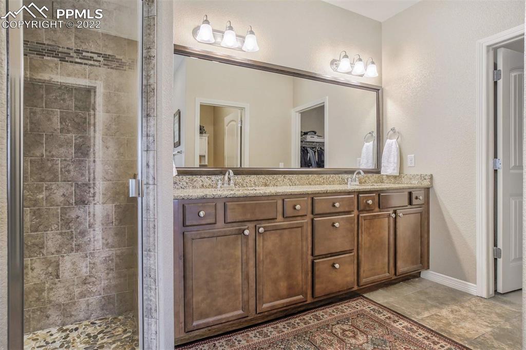 12410 Salmon Point Colorado Springs, CO 80921 - Photo 27 of 49 a bathroom with a granite countertop sink a mirror and a shower
