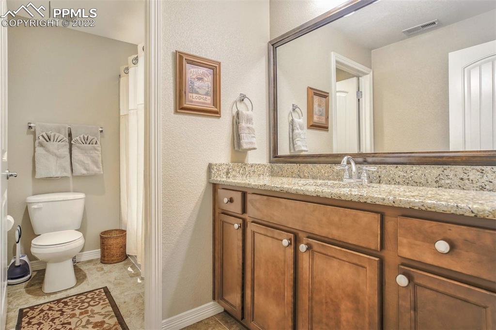 12410 Salmon Point Colorado Springs, CO 80921 - Photo 40 of 49 a bathroom with a granite countertop sink a toilet and a mirror