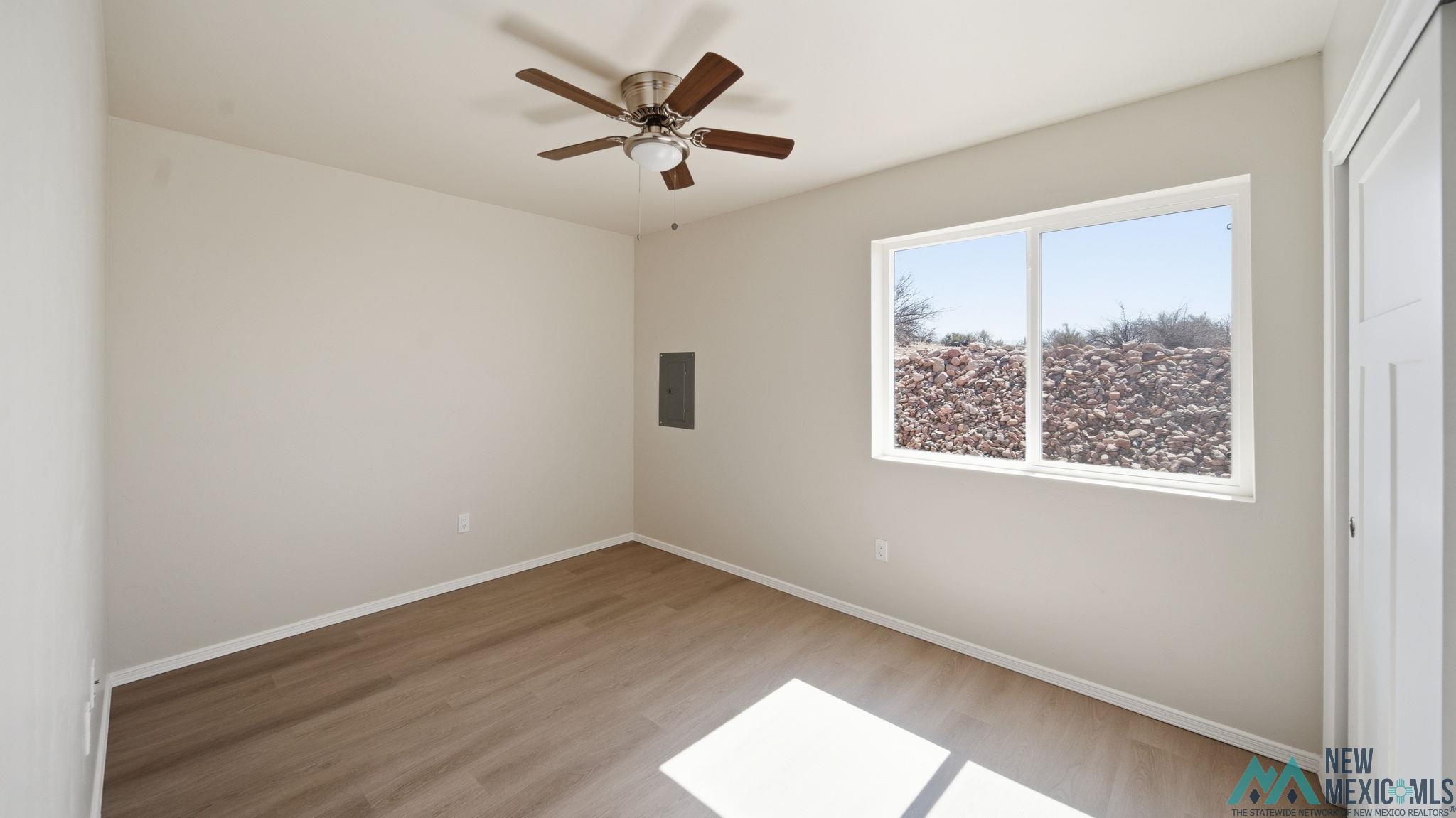 106 Inca Street Elephant Butte, NM 87935 - Photo 33 of 36 Unfurnished bedroom featuring light wood finished floors, a ceiling fan, electric panel, and a closet