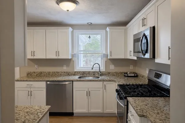 a kitchen with stainless steel appliances granite countertop a stove a sink and a microwave