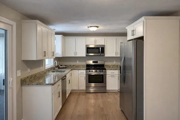 a kitchen with stainless steel appliances granite countertop a refrigerator stove and sink