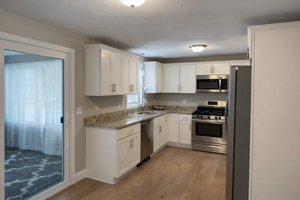 a kitchen with kitchen island granite countertop a stove top oven a sink and dishwasher