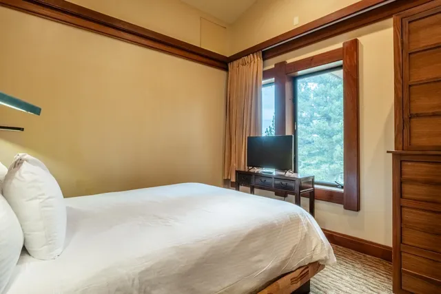 a bedroom with a bed and a flat tv screen next to a window