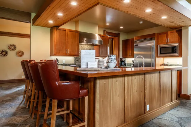 a kitchen with stainless steel appliances kitchen island granite countertop a table chairs in it and wooden floors