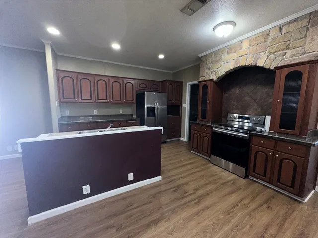 a kitchen with stainless steel appliances granite countertop a stove a sink and a microwave