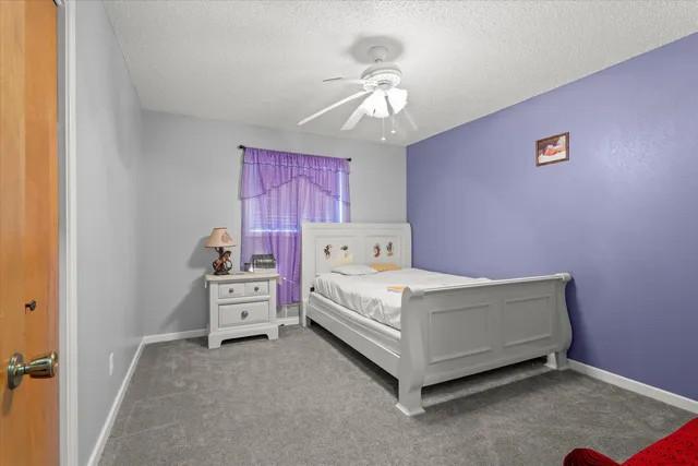 a white bed sitting in a bedroom next to a lamp