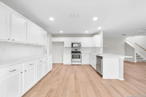 a kitchen with white cabinets and stainless steel appliances