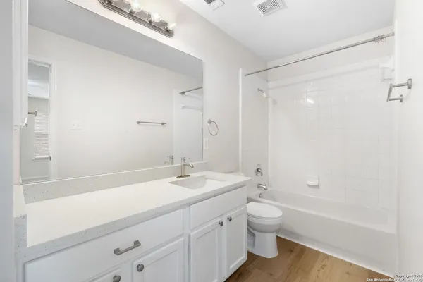 a bathroom with a granite countertop sink a toilet and shower