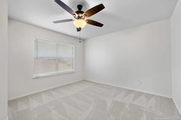 an empty room with a window and a fan
