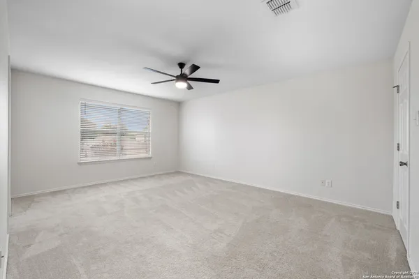 an empty room with windows and ceiling fan