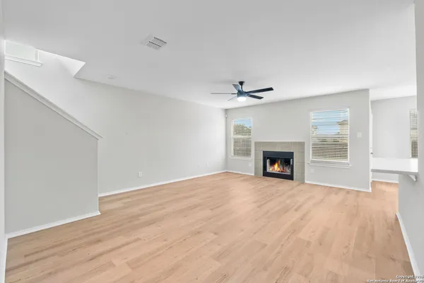 a view of an empty room with wooden floor fireplace and a window