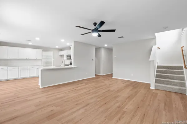a view of an empty room with wooden floor and a ceiling fan