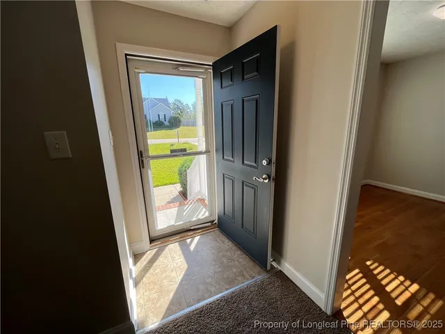 a view of a hallway with wooden floor and a livingroom