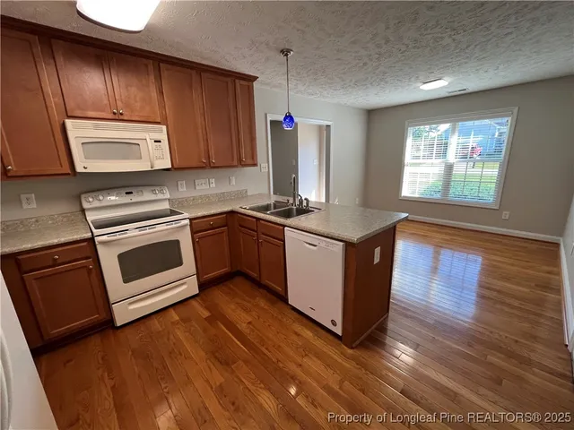 a kitchen with stainless steel appliances granite countertop a sink a stove a microwave a sink and wooden floors